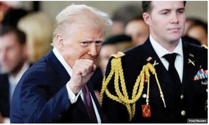 US President Donald Trump gestures with a clenched fist, in front of a member of the US military, during his inauguration ceremony. Pool/Reuters