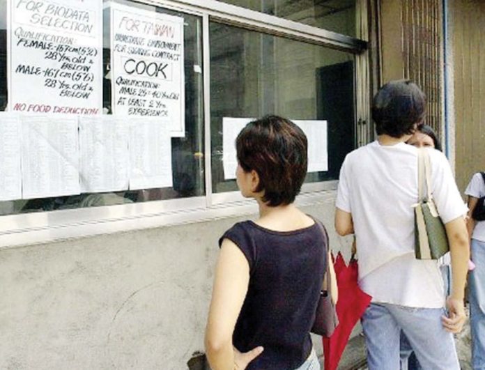 A Filipino woman checks a job placement agency’s announcement in Manila for cooks and factory workers in Taiwan. FILE PHOTO FROM AGENCE FRANCE-PRESSE/ROME GACAD