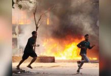 Two men are seen running on the road in Bangladesh. Behind them is a store in flames. Last year’s violence was the worst the country had seen since its 1971 war of independence. GETTY IMAGES