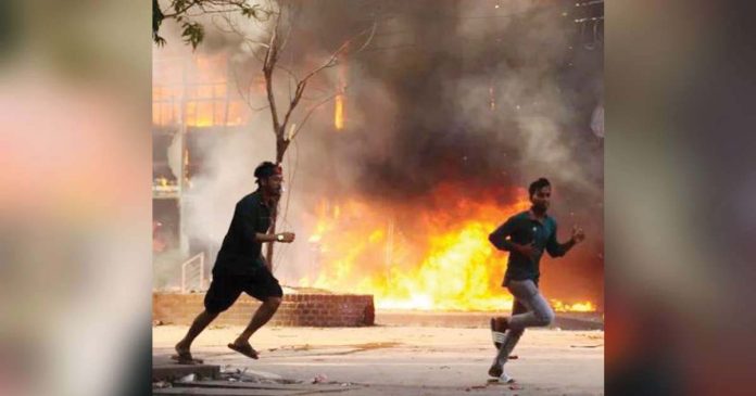 Two men are seen running on the road in Bangladesh. Behind them is a store in flames. Last year’s violence was the worst the country had seen since its 1971 war of independence. GETTY IMAGES