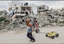 Palestinian children walk past destroyed buildings and makeshift shelters in Beit Lahia, northern Gaza. GETTY IMAGES