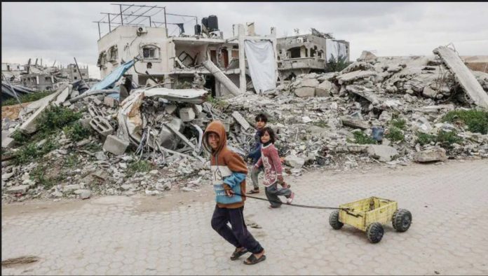 Palestinian children walk past destroyed buildings and makeshift shelters in Beit Lahia, northern Gaza. GETTY IMAGES