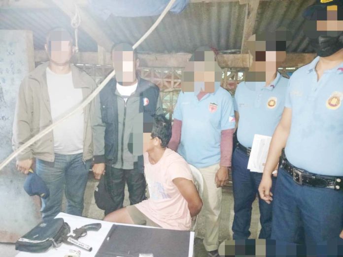 Alias “Bebot” (sitting) was caught with suspected shabu and a 12-gauge shotgun in a raid in Calinog, Iloilo on Monday morning, Feb. 10, 2025. CALINOG MUNICIPAL POLICE STATION PHOTO