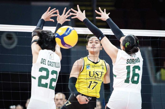 University of Santo Tomas Golden Tigresses’ Angeline Poyos hits the ball between the defense of De La Salle University Lady Spikers’ Lilay del Castillo and Babyjyne Soreno. UAAP PHOTO