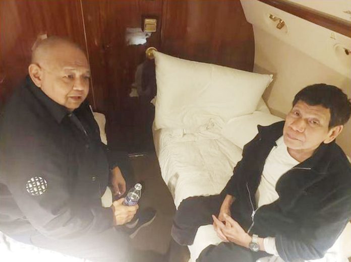 Former President Rodrigo Duterte talks with his former Executive Secretary Salvador Medialdea on board the chartered jet taking them to The Hague, in this picture released by Sen. Bong Go on Wednesday. Photo from REUTERS, AP, SEN. BONG GO/FACEBOOK