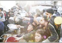 Internally displaced Palestinians hold out bowls to receive Ramadan meals from a charity kitchen in Beit Lahia in the northern Gaza Strip. EPA