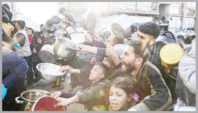 Internally displaced Palestinians hold out bowls to receive Ramadan meals from a charity kitchen in Beit Lahia in the northern Gaza Strip. EPA