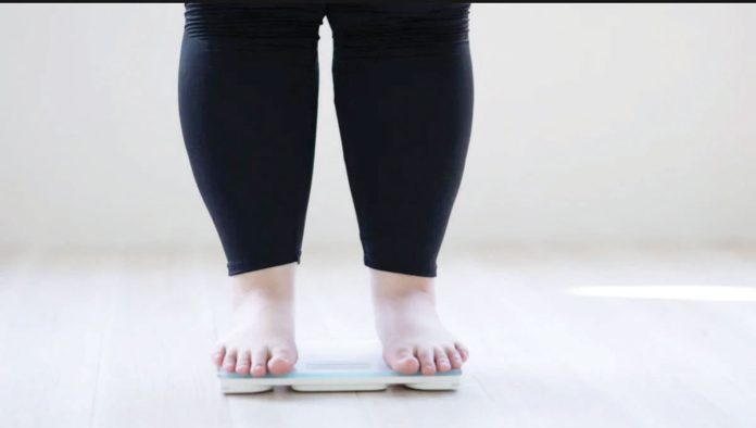 Researchers warn that obesity levels are predicted to accelerate rapidly during the remainder of this decade, particularly in lower-income countries. Photo shows a woman who is overweight standiing on a weighing scale. GETTY IMAGES