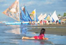 A young girl cools off by playing along the shores of Iloilo City’s Arevalo district, as rising temperatures drive locals to seek relief. In the background, traditional paraws dot the horizon, offering a glimpse of Iloilo’s maritime heritage amidst a looming heatwave. PN