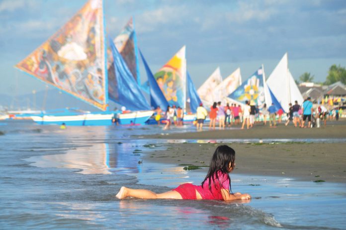 A young girl cools off by playing along the shores of Iloilo City’s Arevalo district, as rising temperatures drive locals to seek relief. In the background, traditional paraws dot the horizon, offering a glimpse of Iloilo’s maritime heritage amidst a looming heatwave. PN