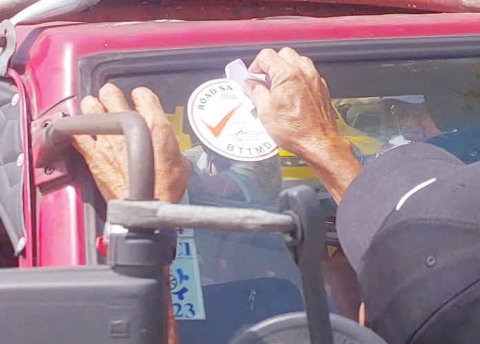 A Bacolod Traffic and Transportation Management Department (BTTMD) officer applies a road safety sticker on a public utility jeepney as part of the ongoing effort to prepare Bacolod City for the phase-out of older jeepneys under the Public Utility Vehicle Modernization Program.